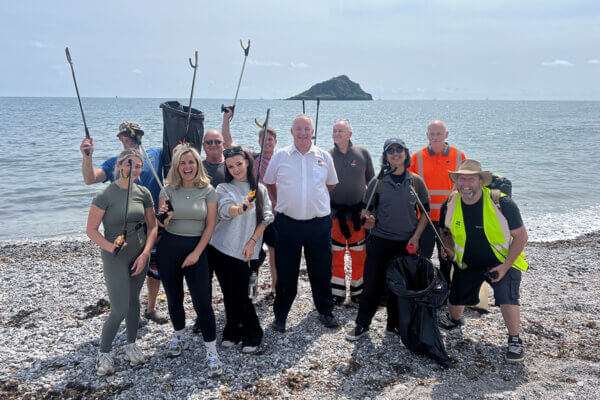 Mitie colleagues at HMS Drake standing on the beach with litter pickers